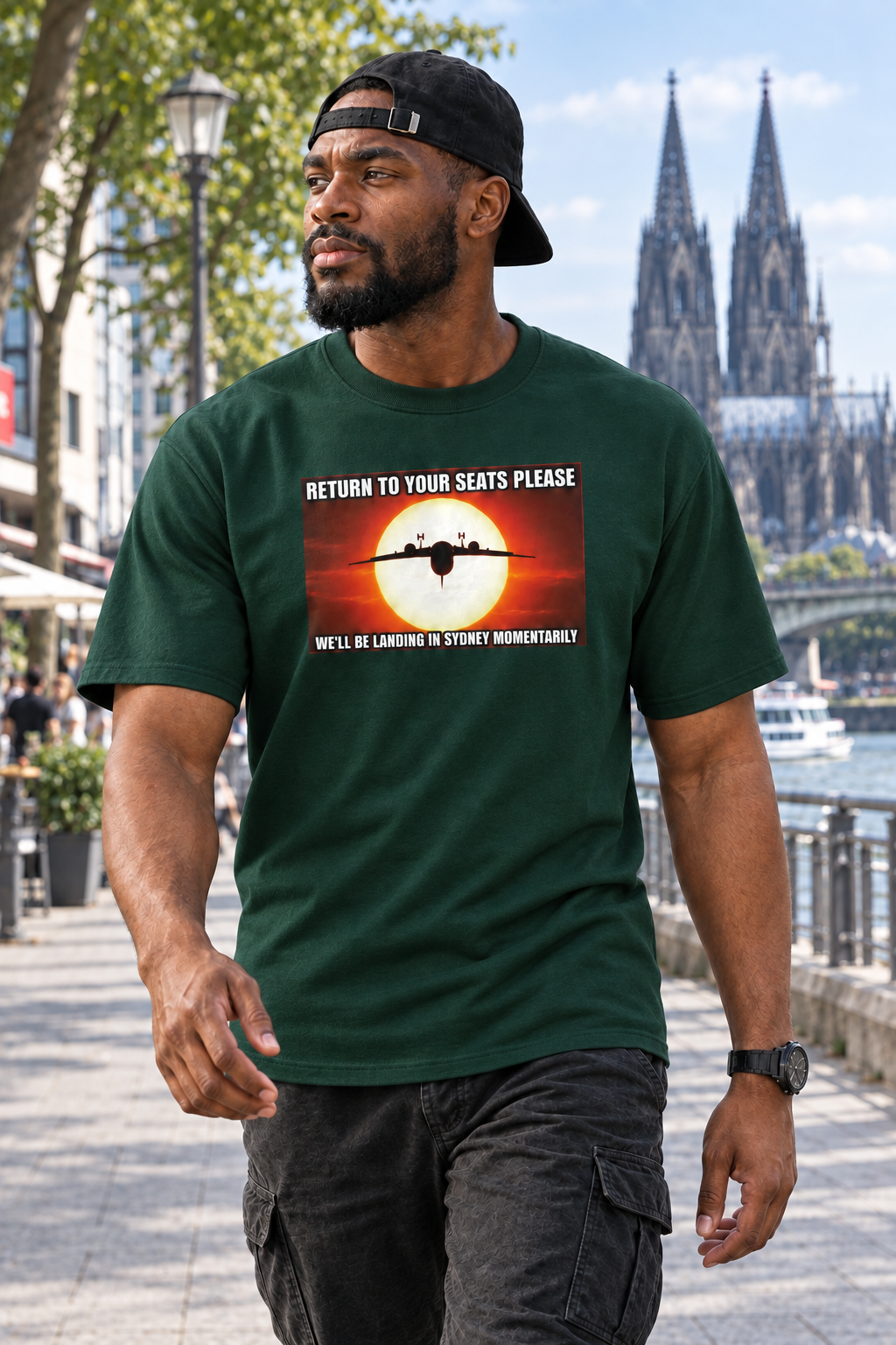 Afrikaanse man met achterstevoren gedragen pet in Forest Green Return to your seats T-shirt, wandelend in Keulen